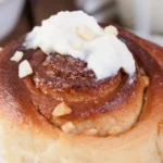 A freshly baked tray of Sourdough Discard Cinnamon Rolls, showcasing their golden-brown tops and swirls of cinnamon sugar, drizzled with creamy icing.