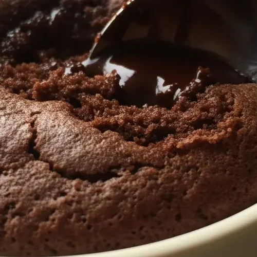 Spoon breaking into a chocolate mug cake with a gooey center